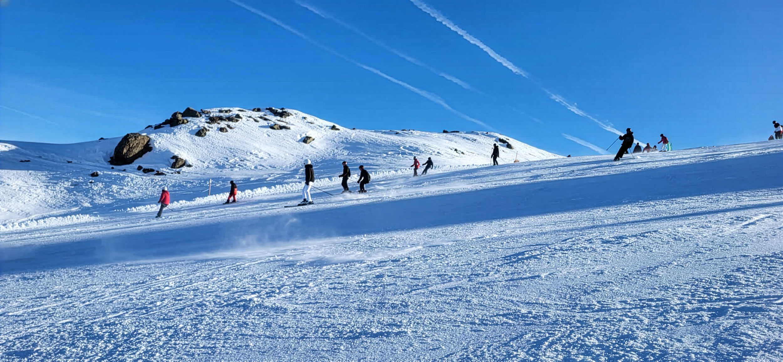 Skifahrer am Hang vor blauem Himmel